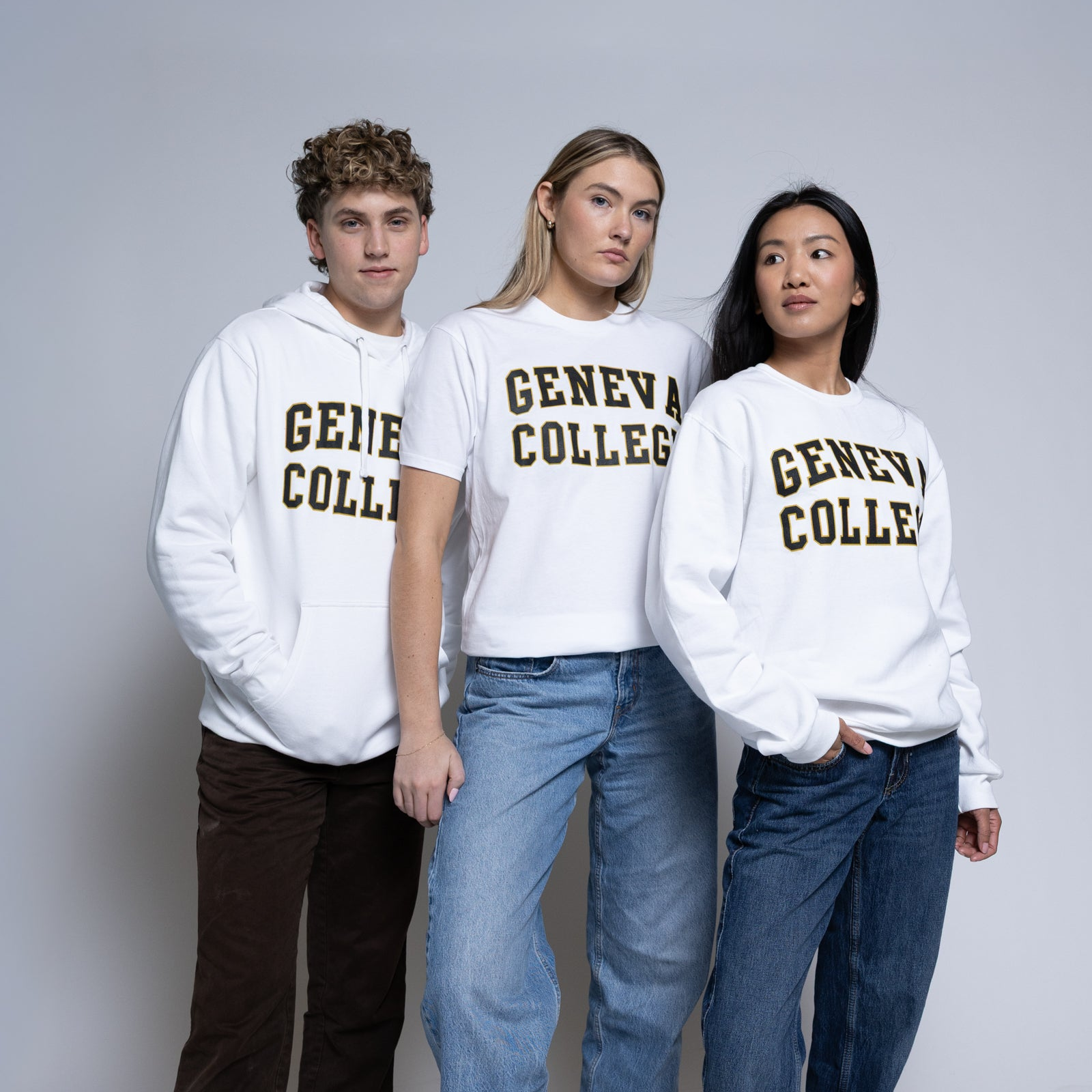 Three people wearing white sweatshirts with 'Geneva College' printed on them against a gray background.