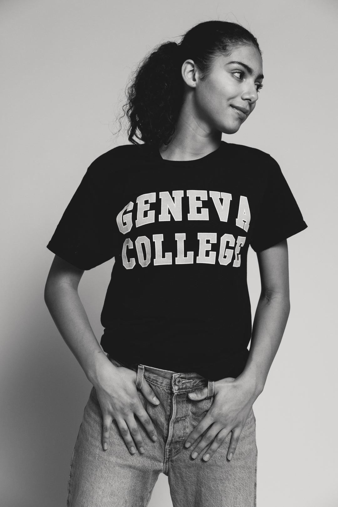 Women wearing a black t-shirt with 'Geneva College' text on a plain background