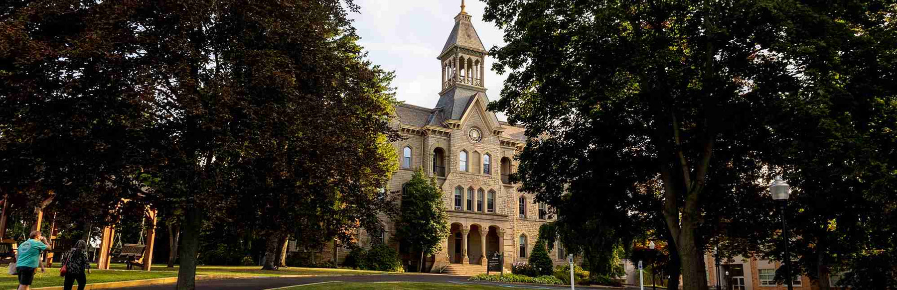 Building on Geneva's Campus with a clock tower surrounded by trees.