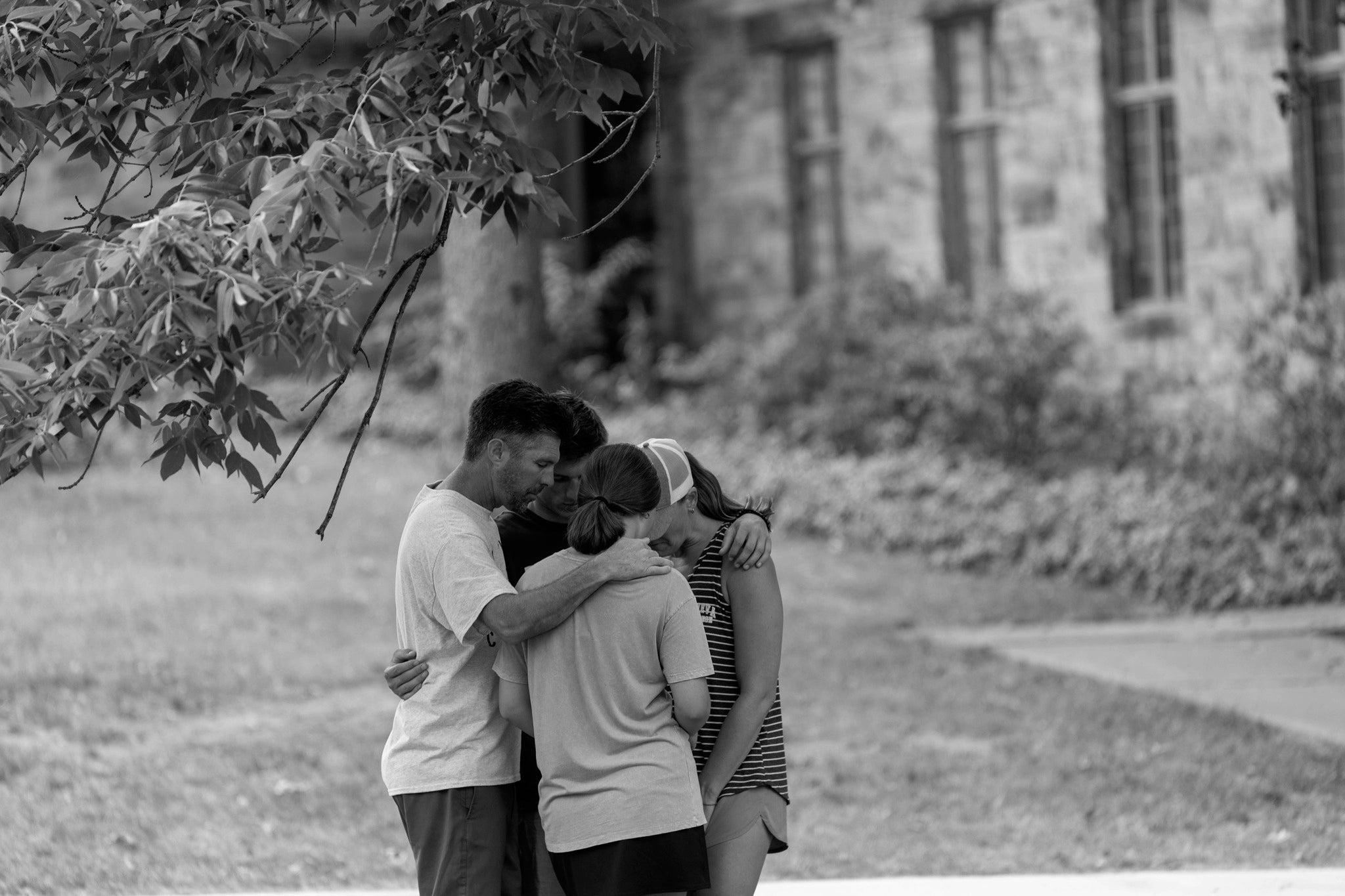 Black and white photo of a family praying outdoors.